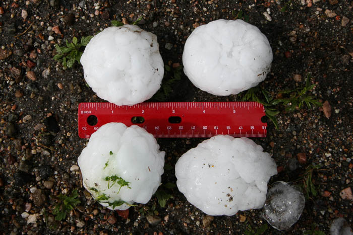 Four large hailstones next to a ruler